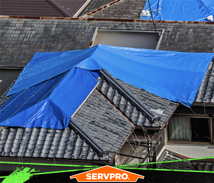 Blue tarp covering the roof of a home .