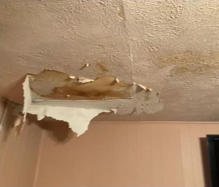 Sagging ceiling with peeled paint and brown water stains