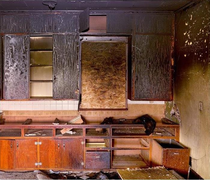 aftermath of kitchen fire; charred and smoke damaged cabinets